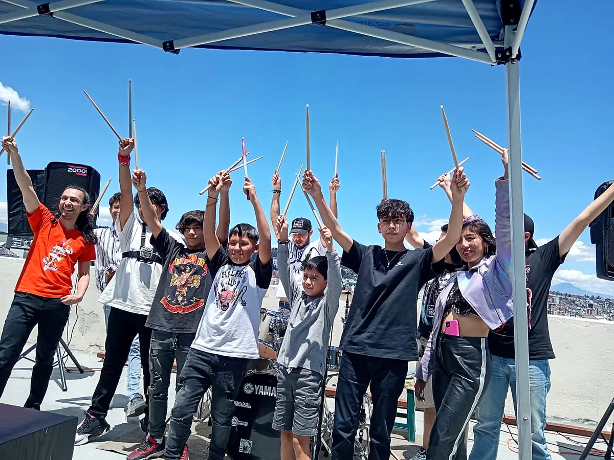 Jorge y estudiantes celebrando con las baquetas en un concierto al aire libre en Quito