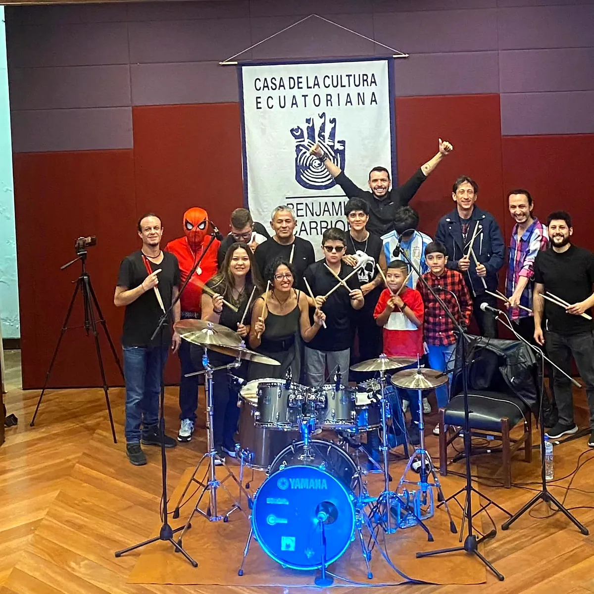 Jorge y estudiantes de SniderDrummer junto a la batería tras un concierto en la Casa de la Cultura Ecuatoriana